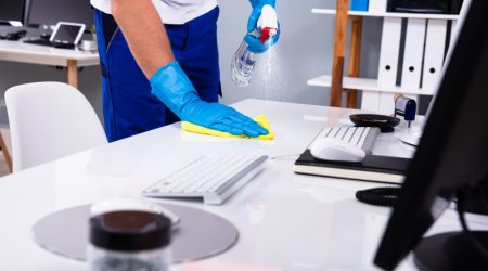 janitor cleaning white desk in office